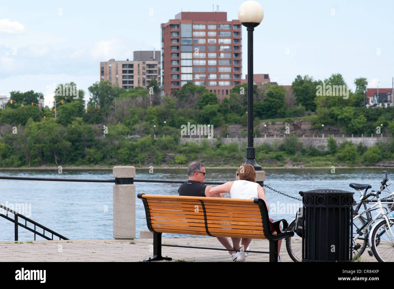 Pareja de ancianos sentados en un banco mirando el río Ottawa, Ottawa, Ontario, Canadá Foto de stock
