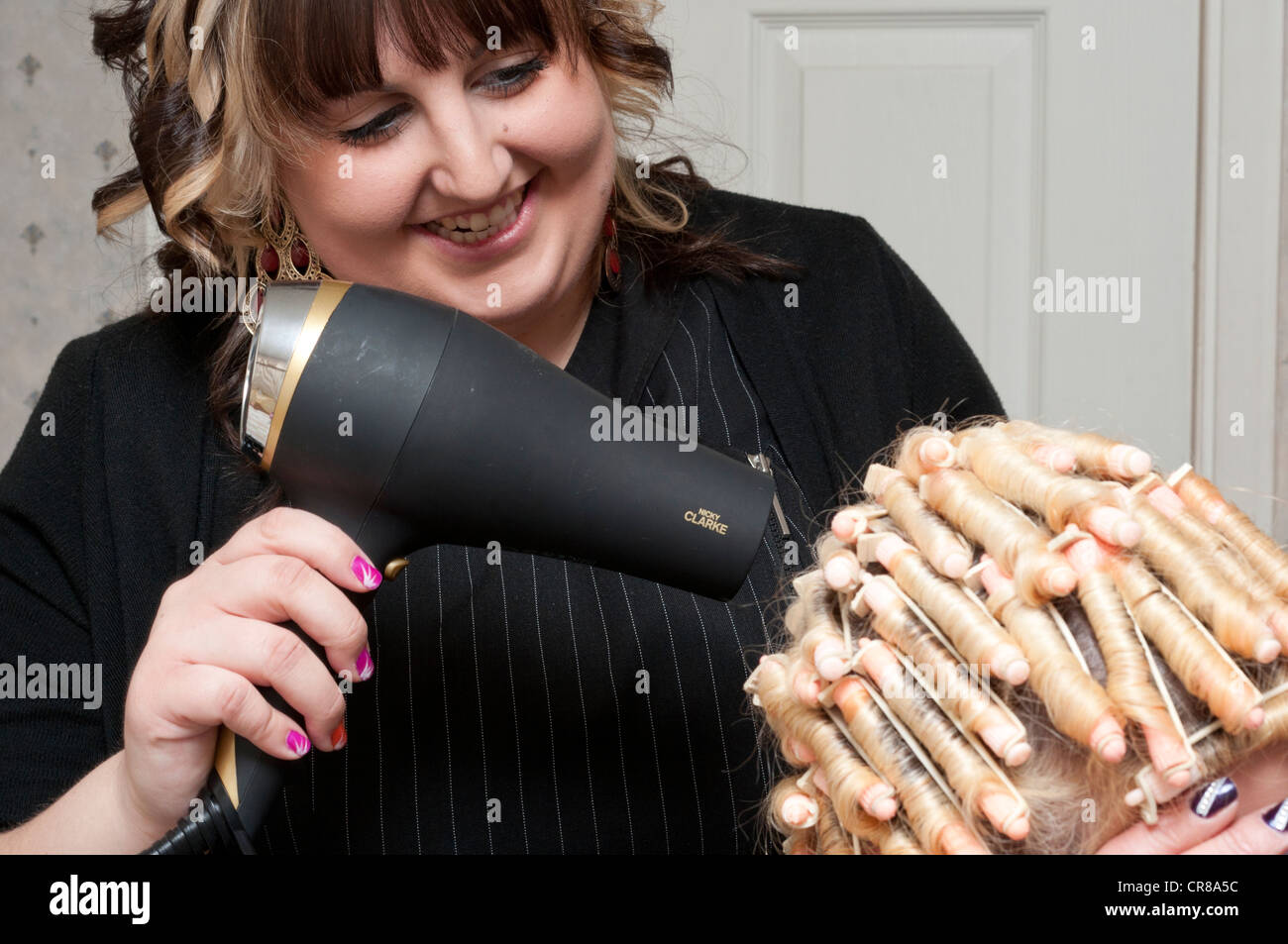 Peluquería móvil utilizando un secador de pelo mientras para moldear el  cabello Fotografía de stock - Alamy