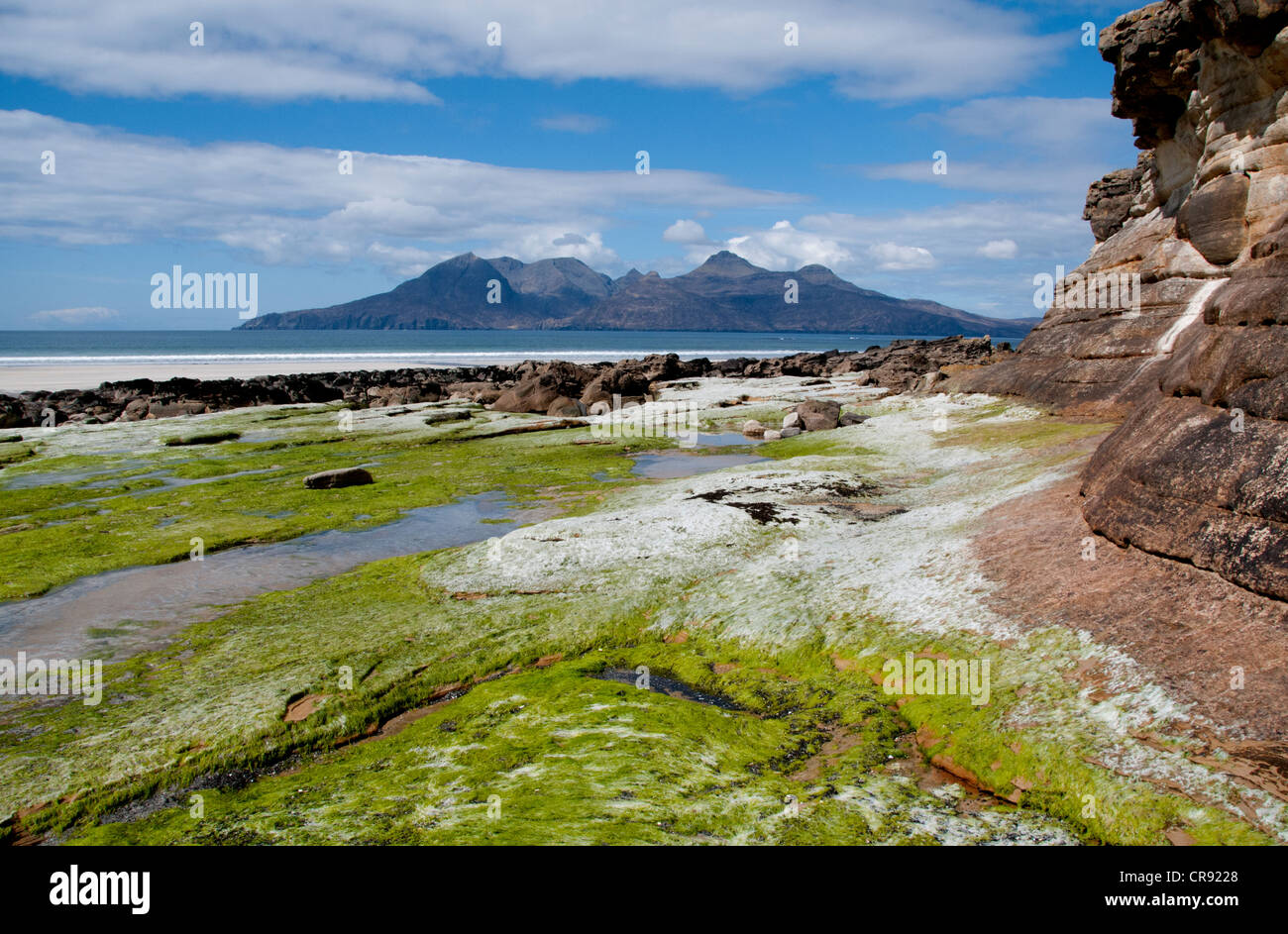 Un paisaje de la bahía de laig en la isla de eigg con la isla de ron en la parte trasera del terreno con buen interés en primer plano Foto de stock