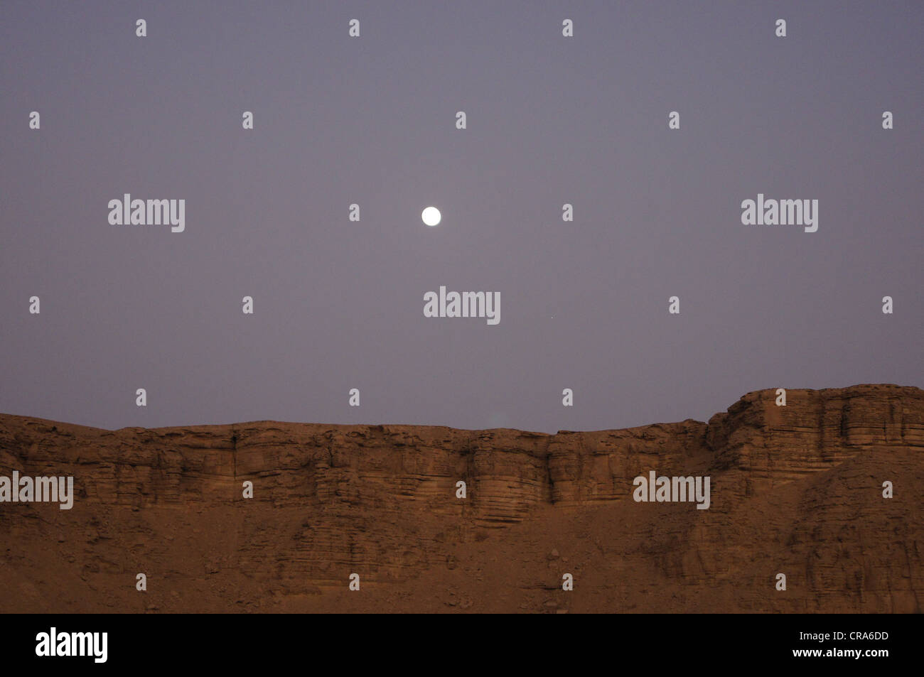 La luna saliendo sobre formaciones rocosas en el desierto de arena roja - Riad, Reino de Arabia Saudita Foto de stock
