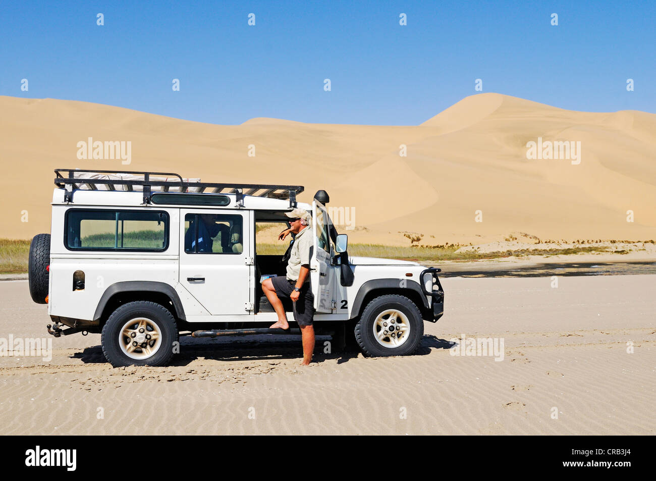 Hombre con un Landrover Defender vehículo off-road en los humedales de Sandwich Harbour, el Parque Nacional Namib-Naukluft Foto de stock