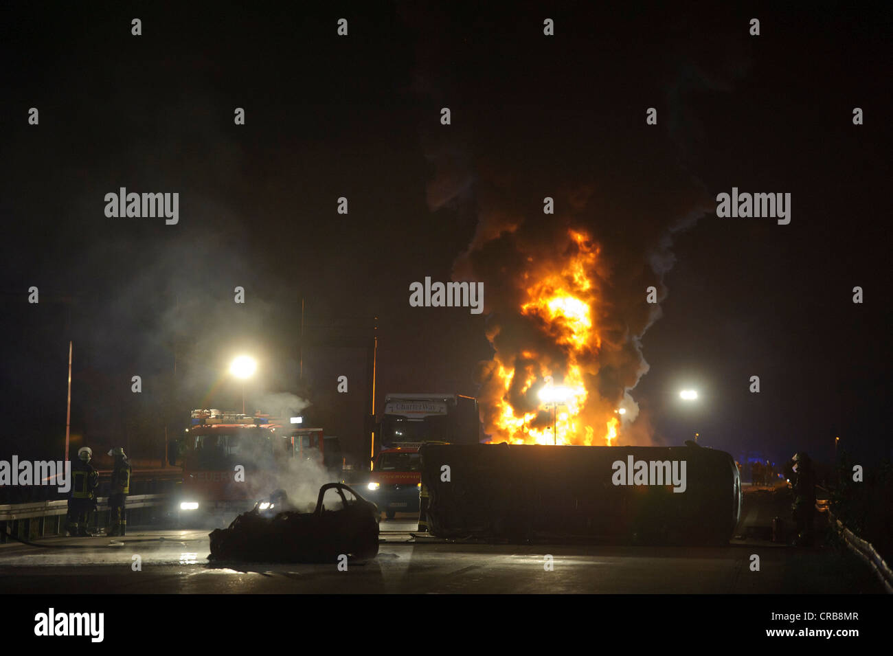 Totalmente quemado coches deportivos BMW junto a un furgón de transporte tumbado delante de un camión ardiendo y un camión tanque de aceite Foto de stock