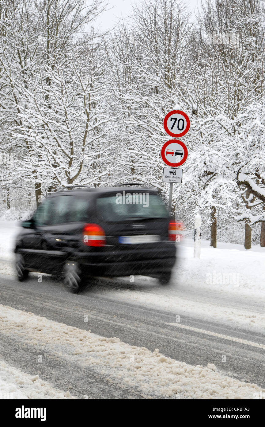 País por carretera cubiertas de nieve en invierno, obligatorio-signo, signo de prohibición, el coche, el desenfoque de movimiento Foto de stock