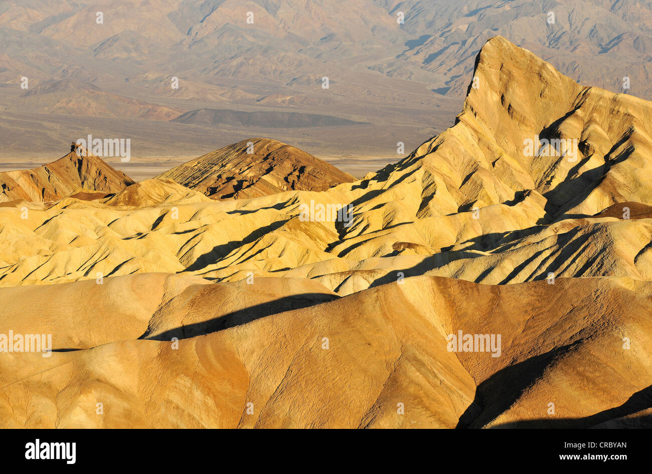 Vista de Zabriskie Point hacia Manly baliza con rocas erosionadas por minerales descolorida, con Panamint Range en la distancia Foto de stock