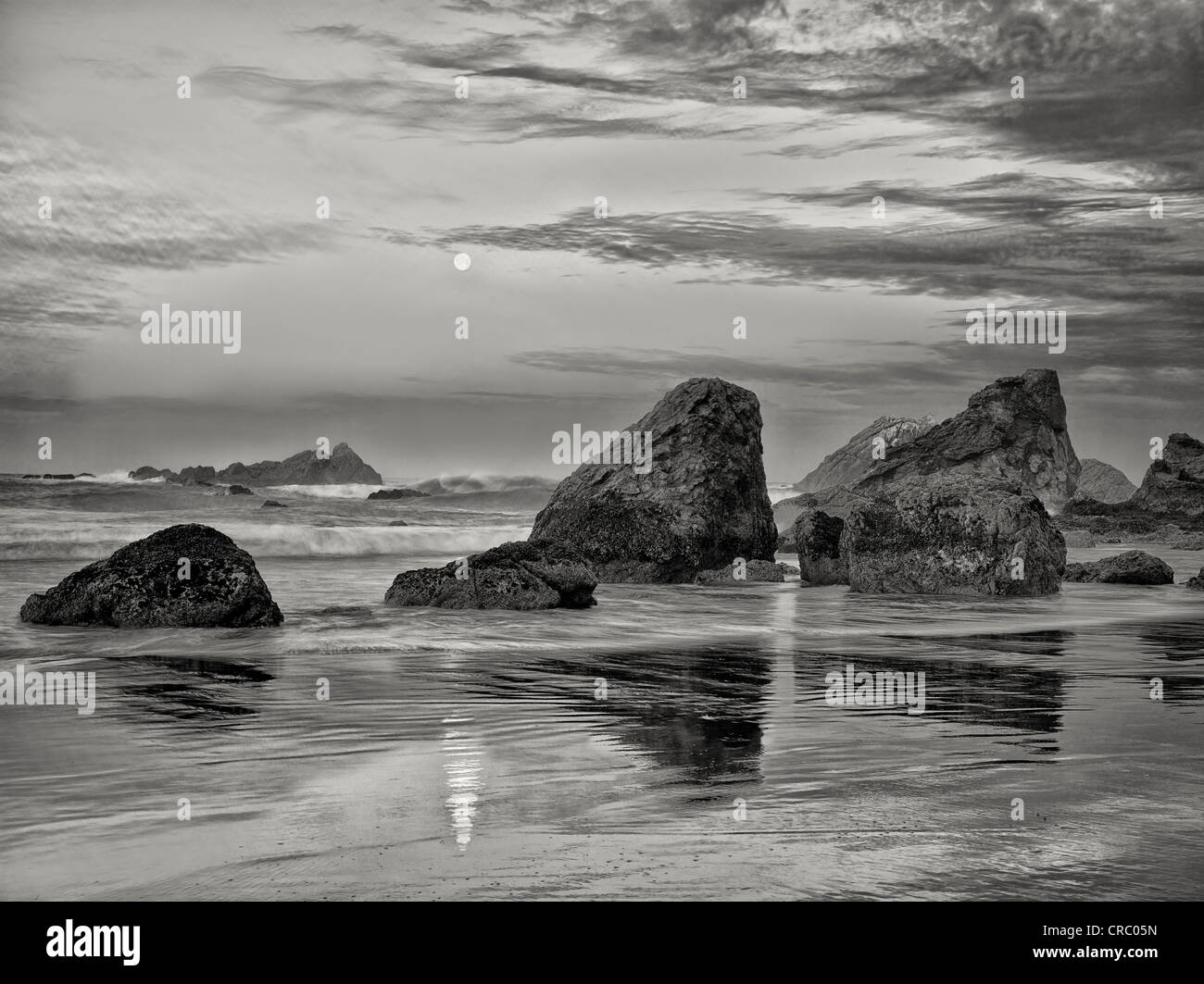 Amanecer y plena moonset con reflexión en Harris Beach State Park, Oregón Foto de stock