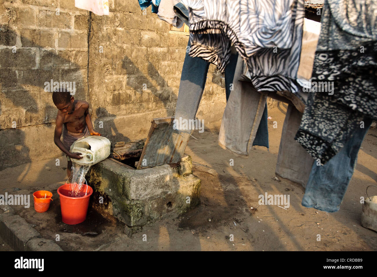 Un niño dibuja el agua de un pozo en la barriada de West Point en Monrovia, la capital del condado de Montserrado, Liberia el lunes 2 de abril, 2012. Foto de stock