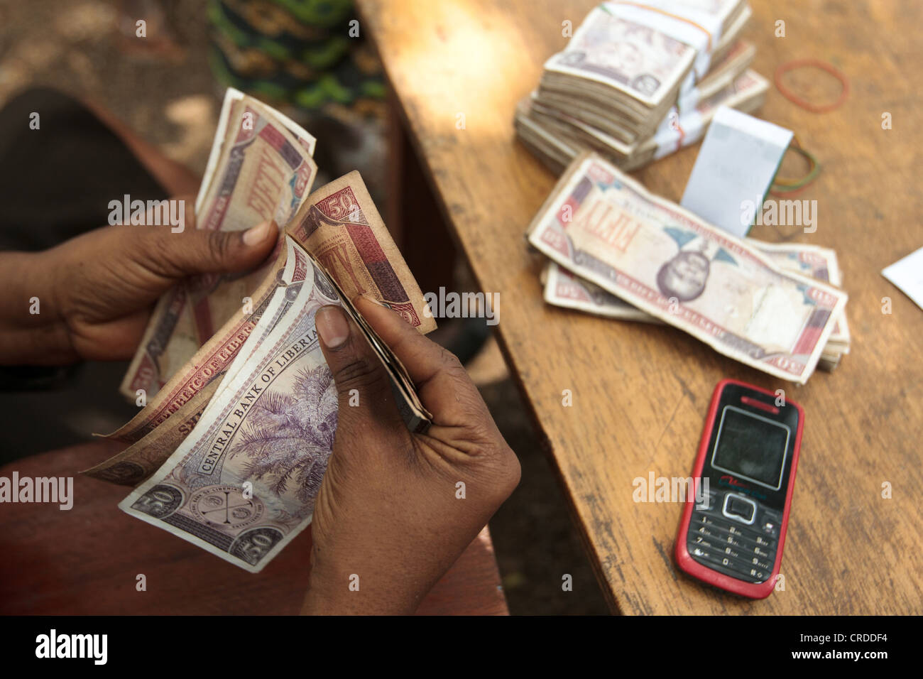Un funcionario de un banco local cuenta dinero durante una distribución de programas sociales de transferencias en metálico en la aldea de Julijuah Foto de stock