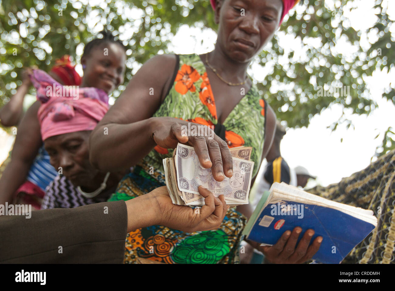 Una mujer recibe dinero durante una distribución de programas sociales de transferencias en metálico en la aldea de Julijuah, condado de Bomi, Liberia Foto de stock