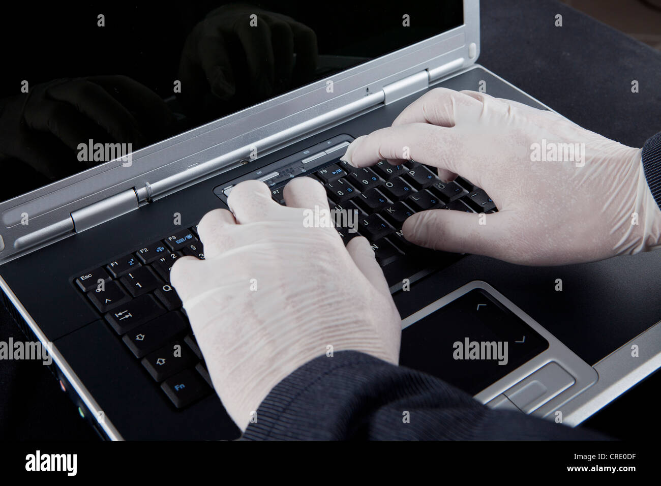 Hacker usando un equipo portátil, usar guantes de látex para no dejar rastros, imagen simbólica de la criminalidad en Internet Foto de stock