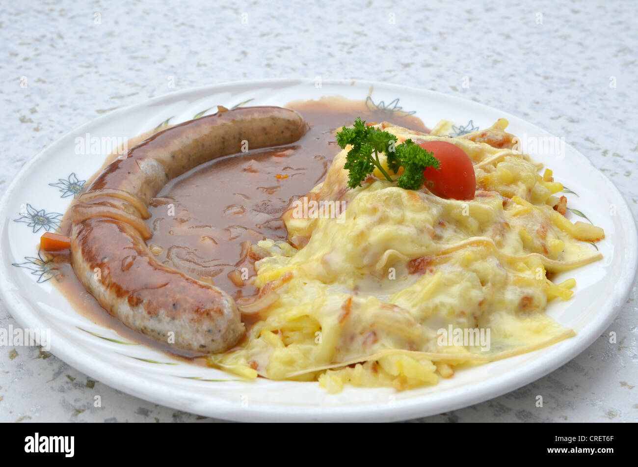 La cena tradicional alemana de Bratwurst servida con una salsa de cebolla y queso encabezó la patata rosti - Enfoque selectivo Foto de stock