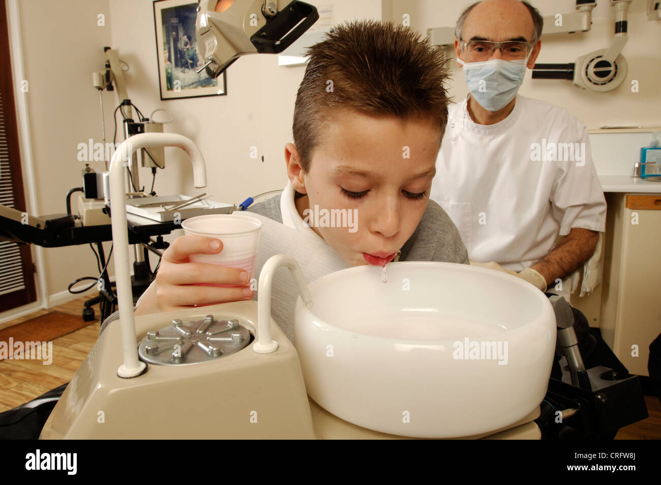 Un muchacho se enjuaga la boca con una solución anti-microbiana antes de someterse a tratamiento. Foto de stock