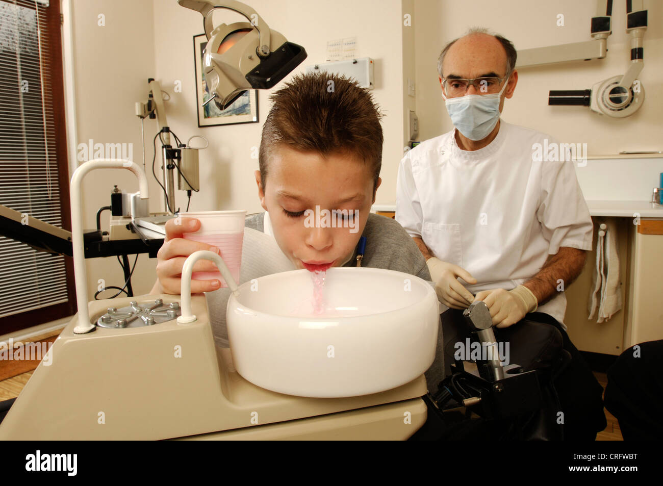 Un muchacho se enjuaga la boca con una solución anti-microbiana antes de someterse a tratamiento. Foto de stock