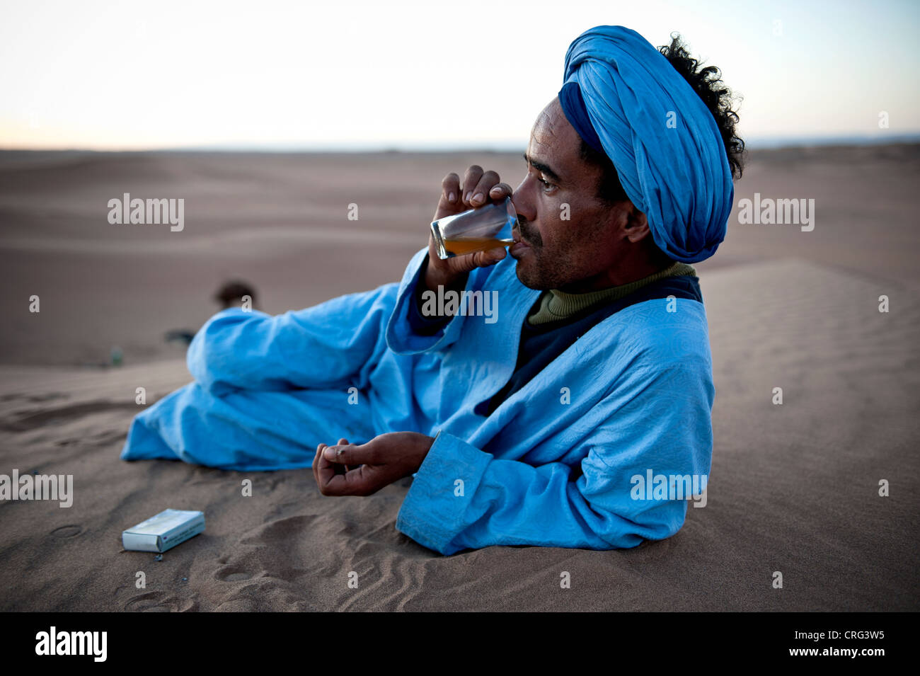 Nómada bereber beber té en el desierto del Sáhara, Erg Chigaga, Marruecos Foto de stock