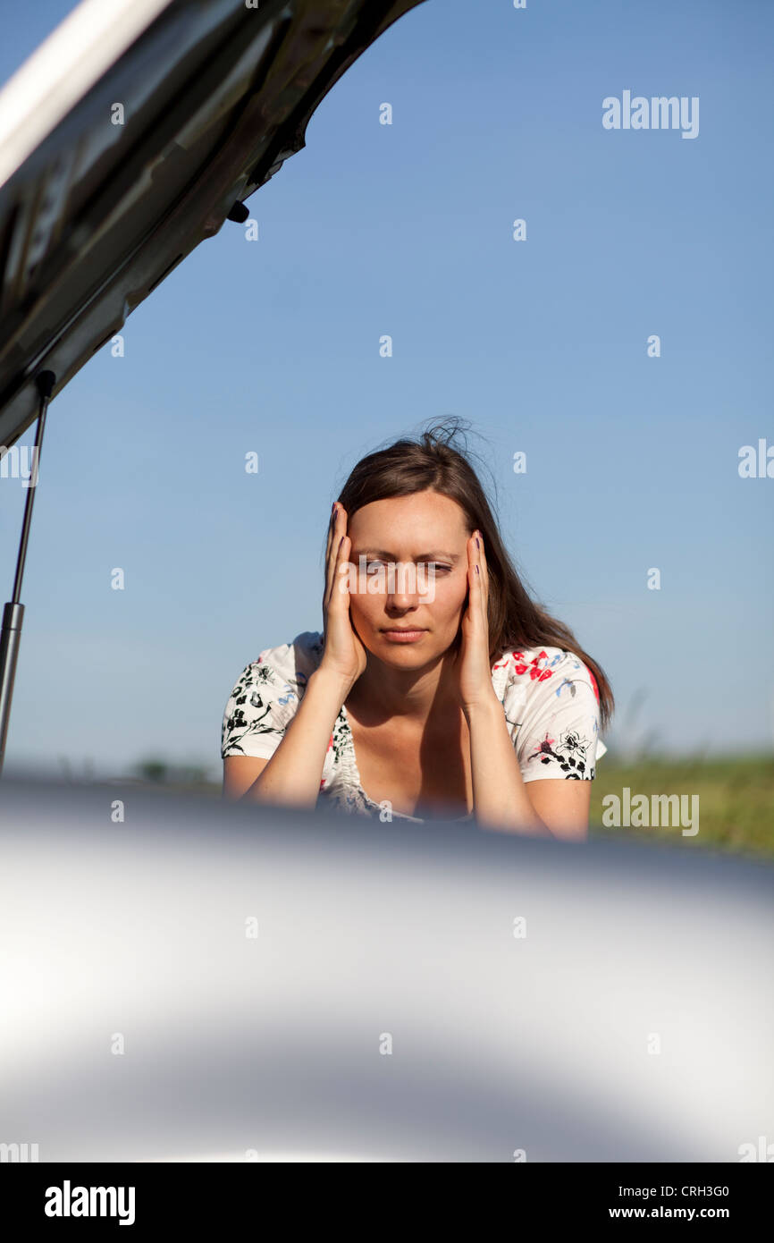 Mujer mirando el motor de un coche rotos Foto de stock