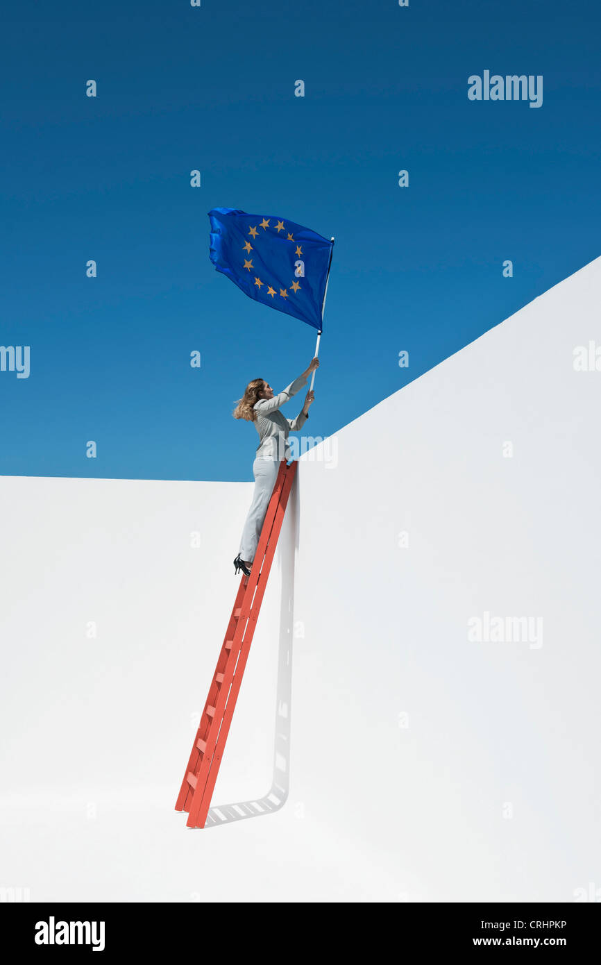 La empresaria de pie en la parte superior de la escalera, sosteniendo la bandera de la Unión Europea Foto de stock
