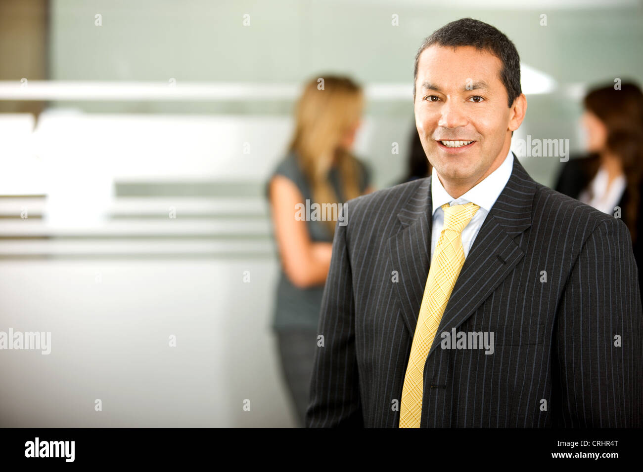 Empresario con traje negro con corbata amarilla, sonriendo Foto de stock