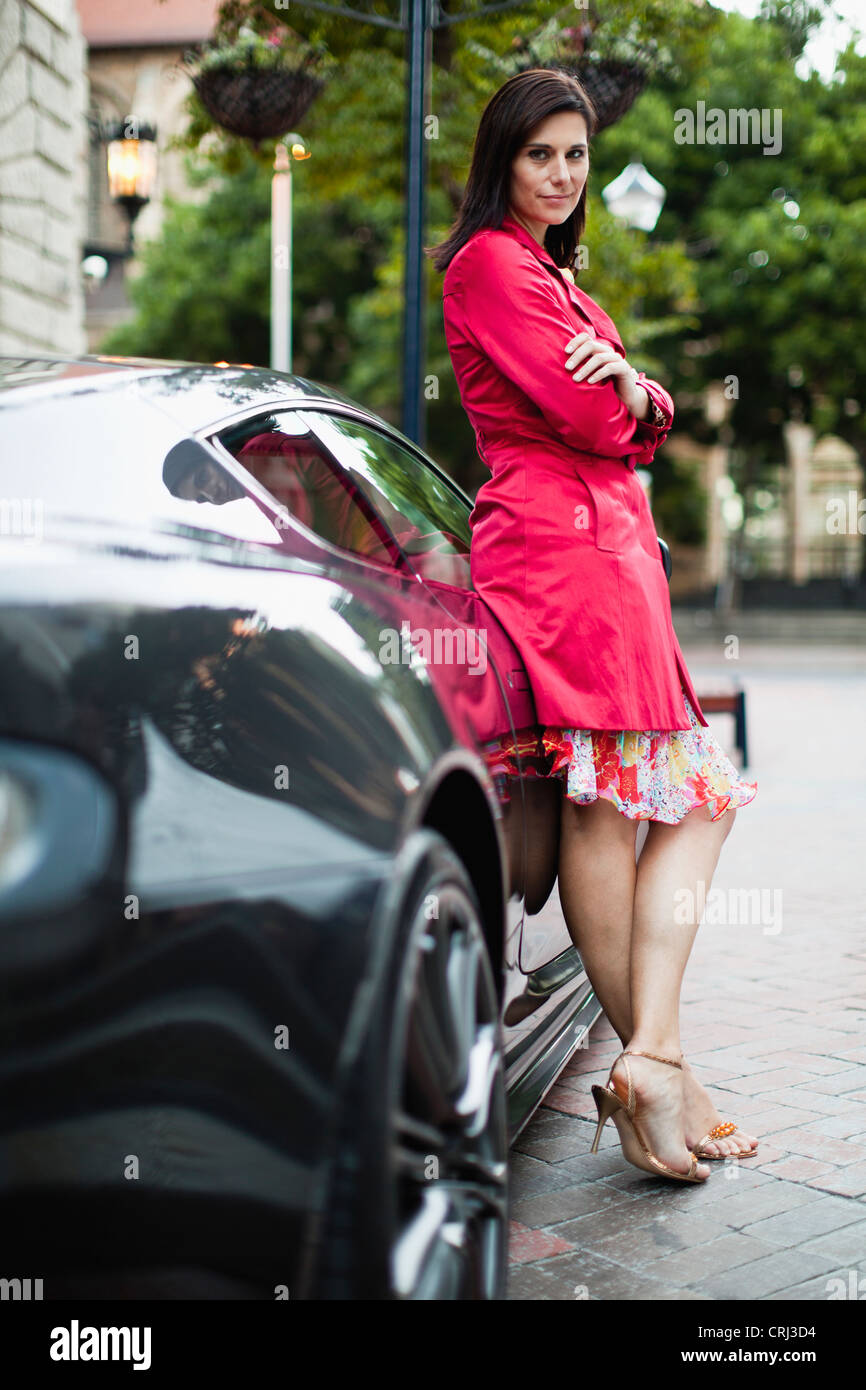 Mujer sonriente apoyado en coche deportivo Foto de stock