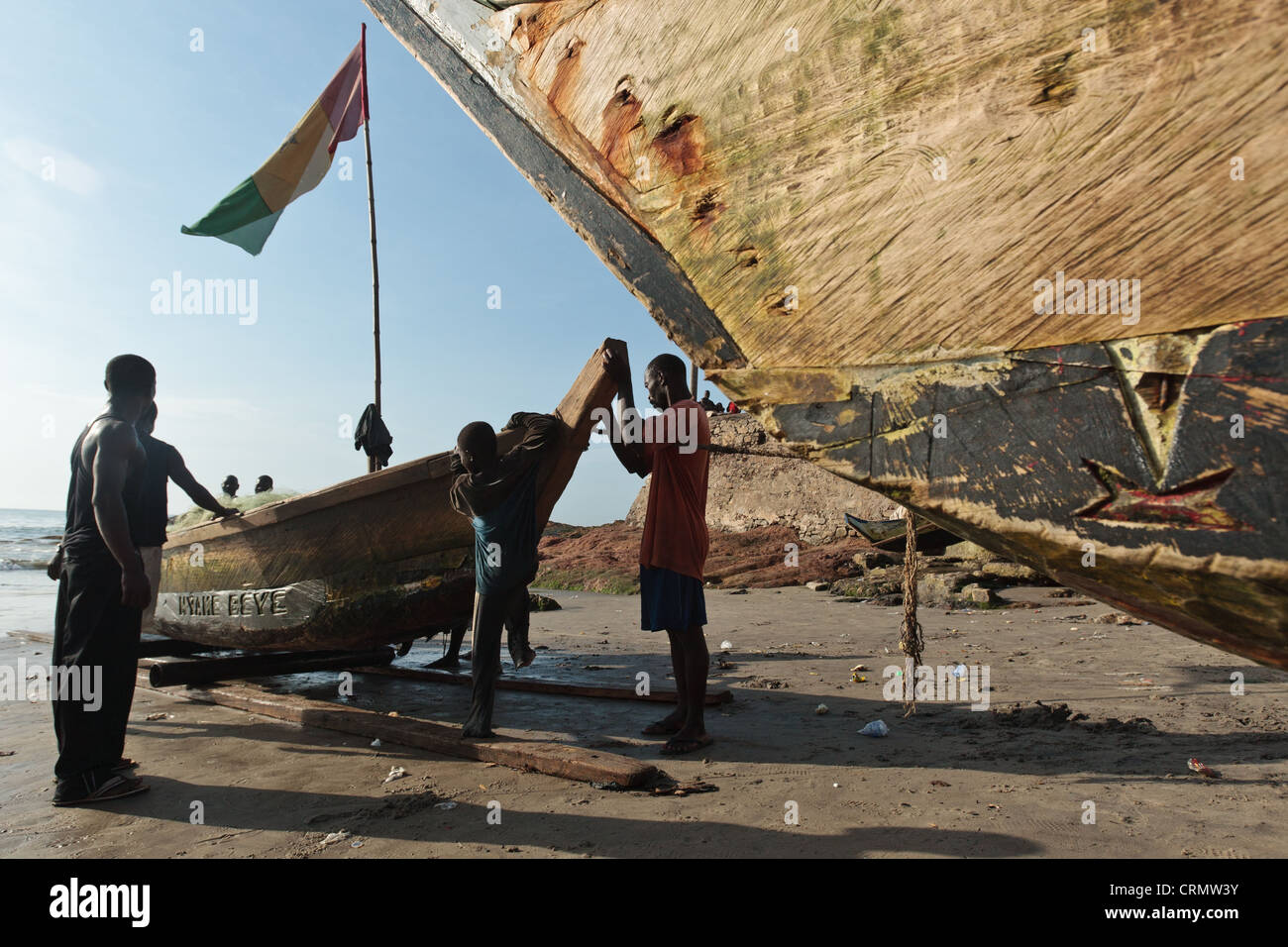 Los pescadores tirando de su barco en la playa de Cape Coast, Ghana Foto de stock