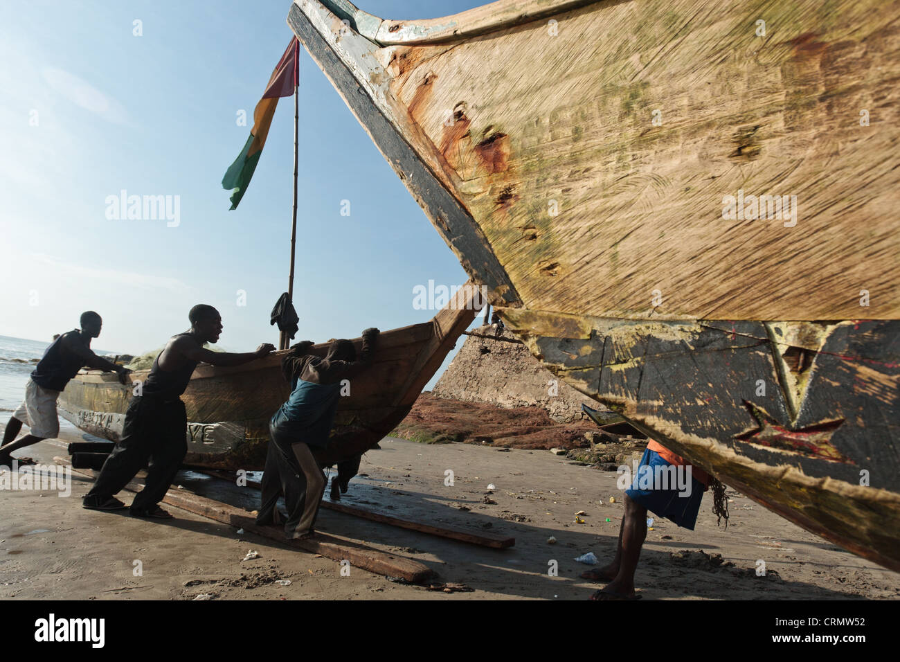 Los pescadores tirando de su barco en la playa de Cape Coast, Ghana Foto de stock