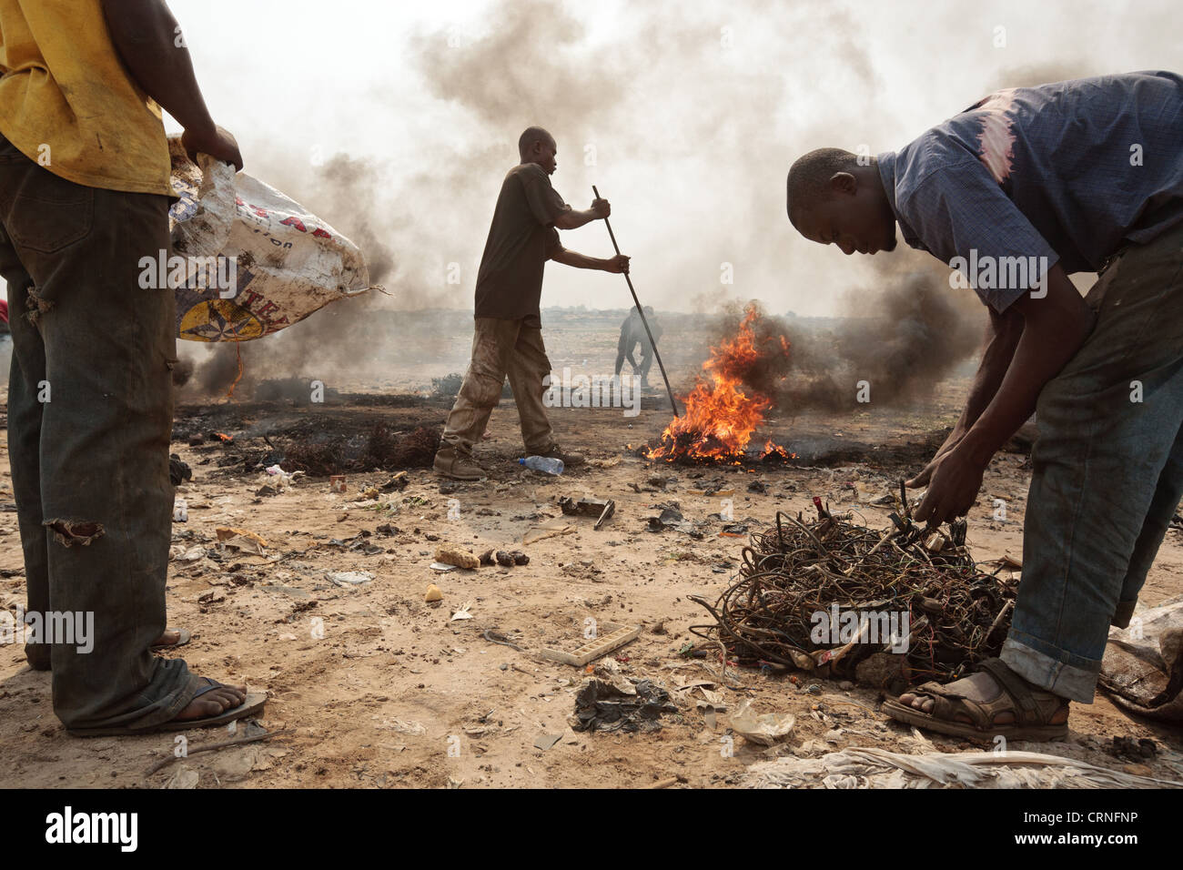 Muchachos adolescentes quemar los cables de ordenadores y otros equipos electrónicos para recuperar cobre cerca del tugurio Agbogboloshie en Accra, Ghana Foto de stock