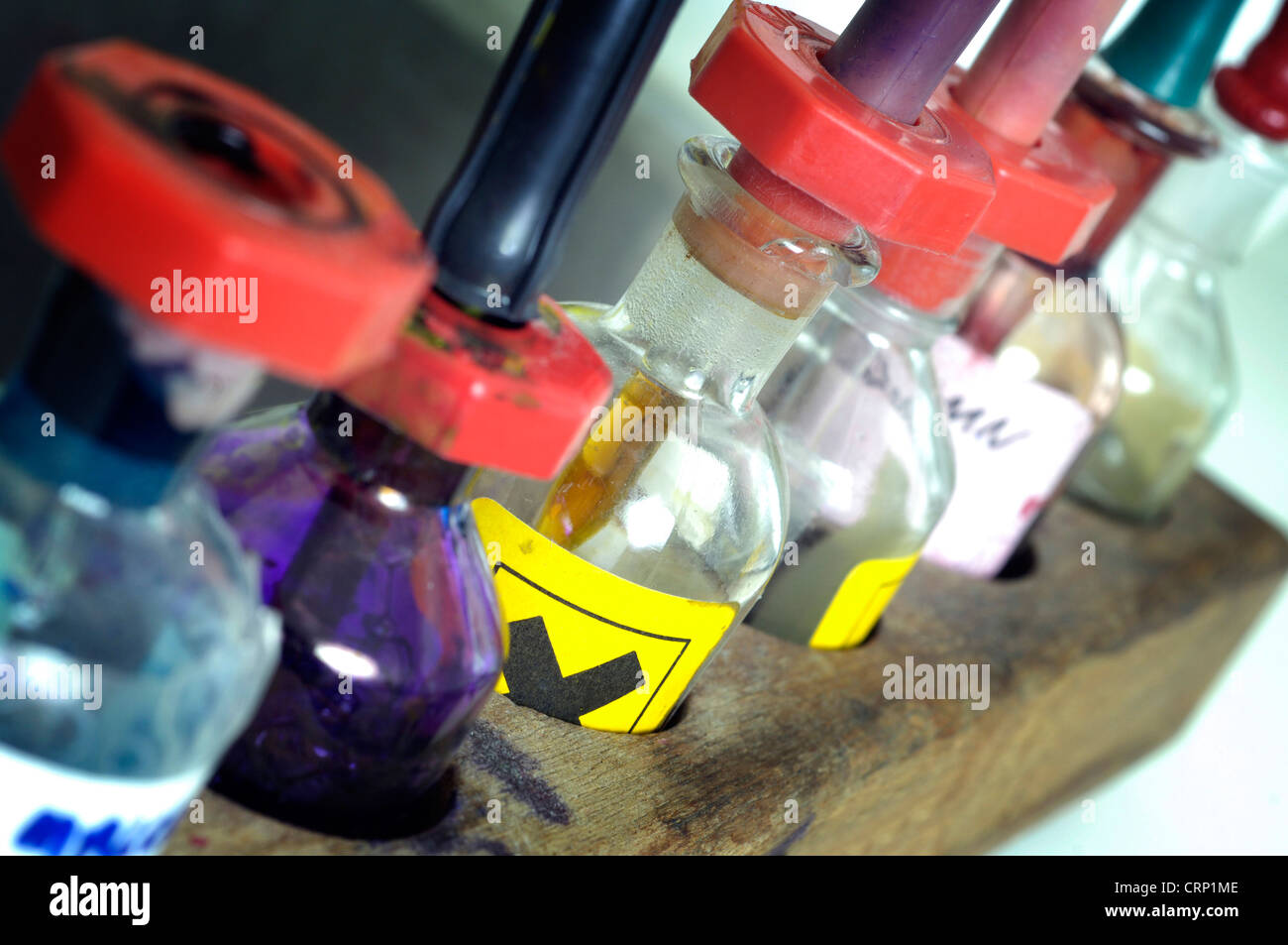 Un rack de botellas de pipeta, algunos que contienen líquidos nocivos, sobre un banco de trabajo de laboratorio. Foto de stock
