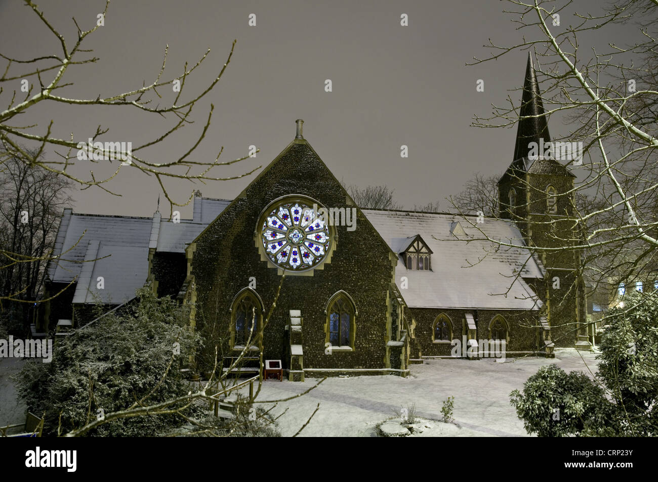 Iglesia en la nieve durante la noche, con luces interiores brillando a través de una vidriera, la Iglesia de Todos Los Santos, Belvedere, en Bexley, Kent, Foto de stock