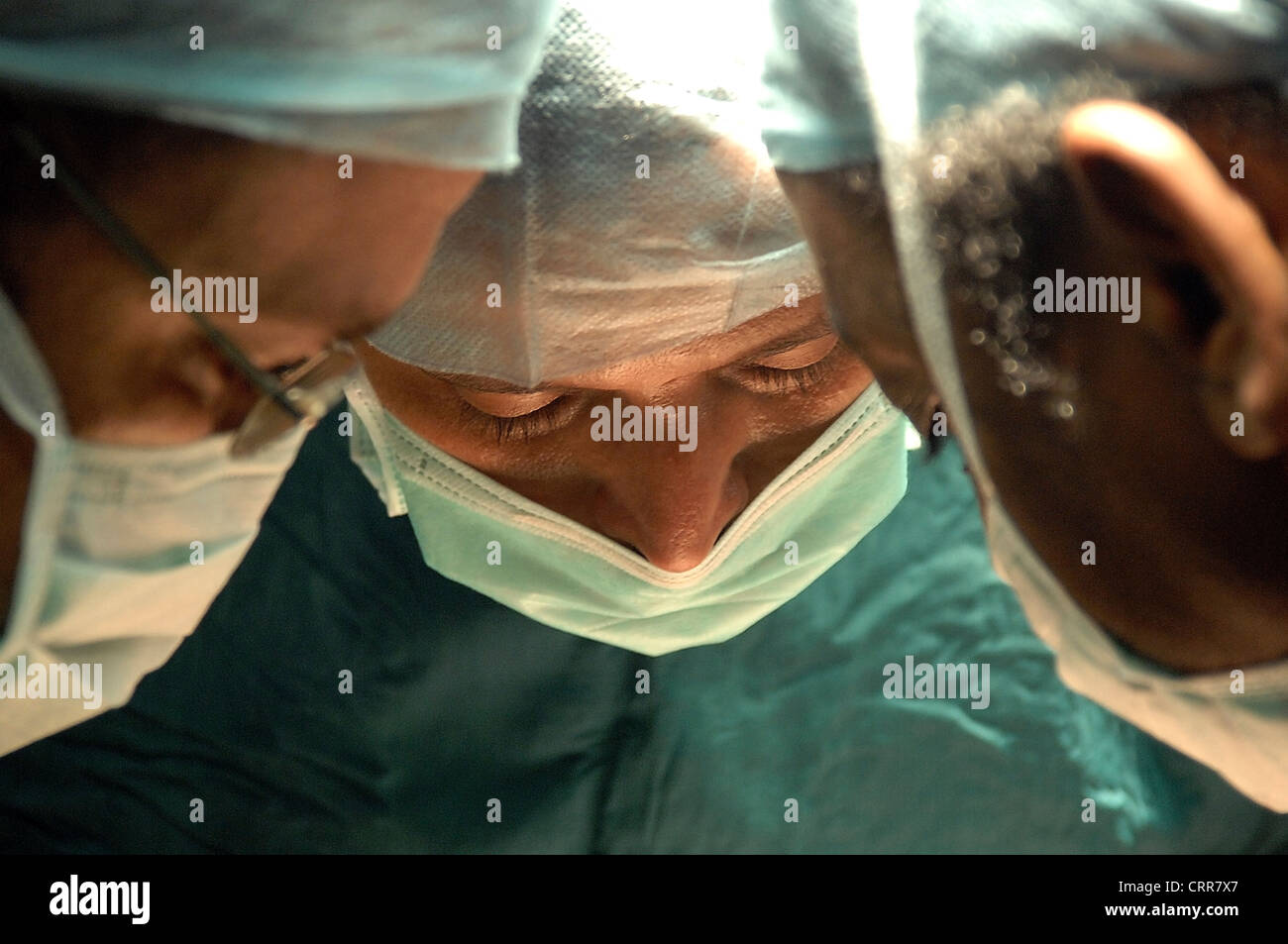 Tres cirujanos operan en un paciente. Foto de stock