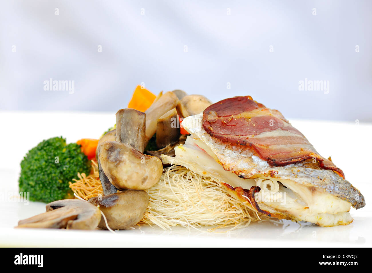 Comida fusión con tocino, pescados, verduras y pastas Foto de stock