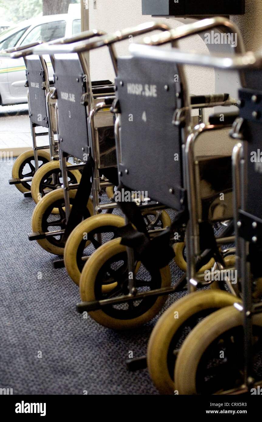 Una línea de sillas de ruedas en un hospital a la espera de pacientes Foto de stock