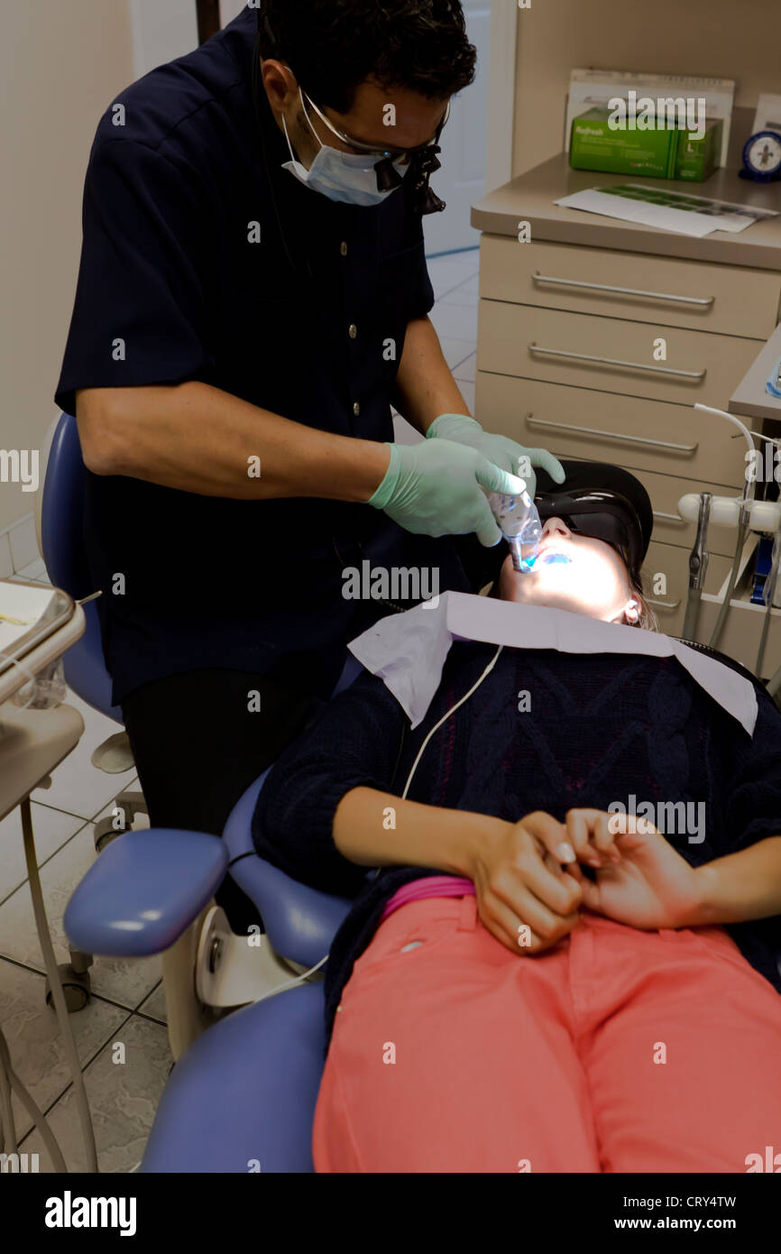 Odontólogo tratar una cavidad mientras el paciente está viendo una película Foto de stock