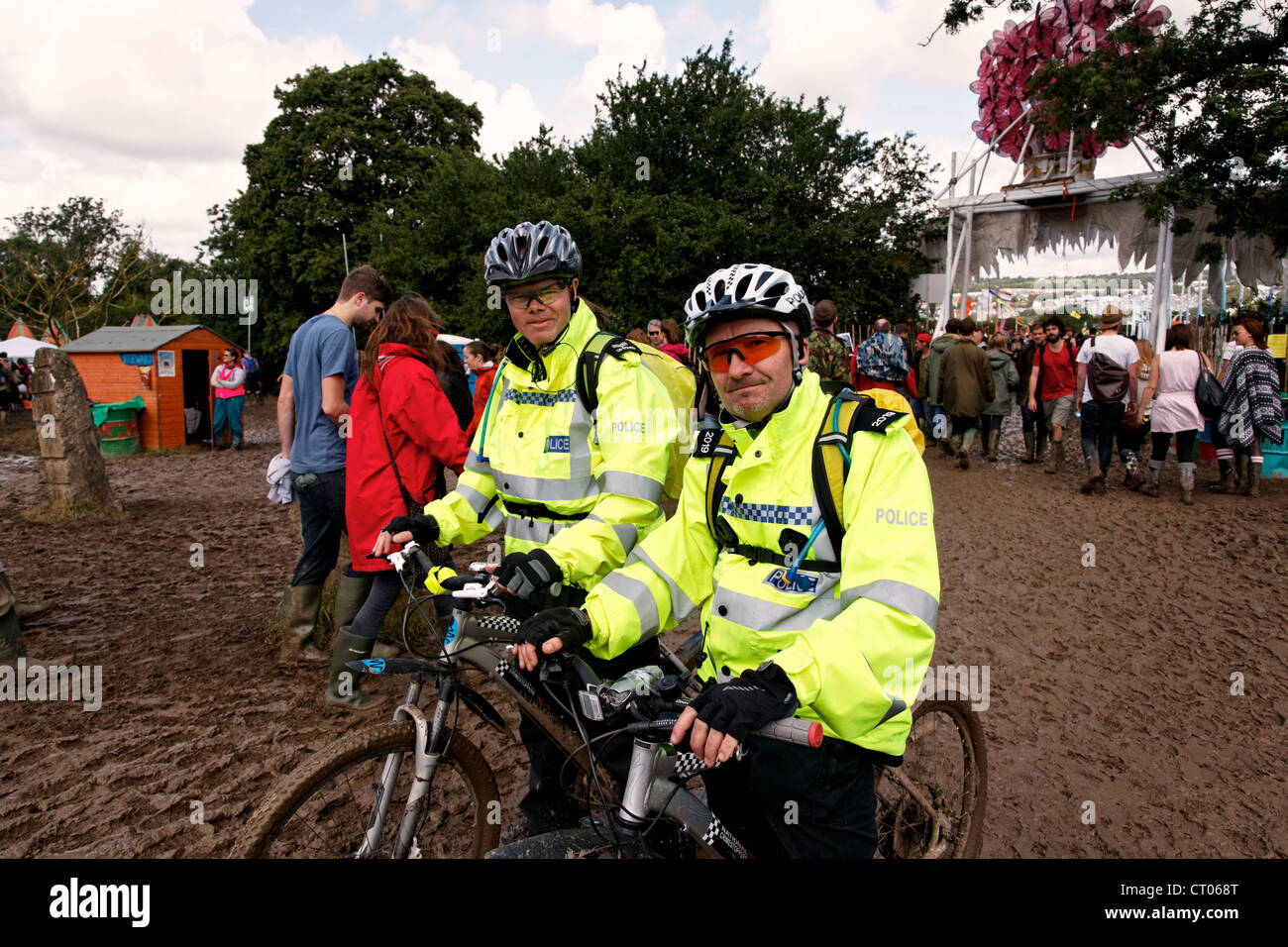Dos policías utilizar bicicletas para ayudarles a conseguir a través del barro en el Festival de Glastonbury. Foto de stock