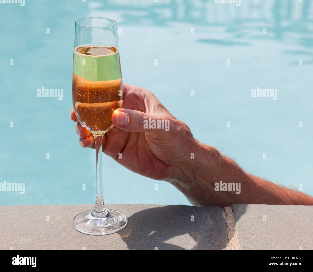 Hombre bebiendo champán / vino mientras en la piscina Foto de stock