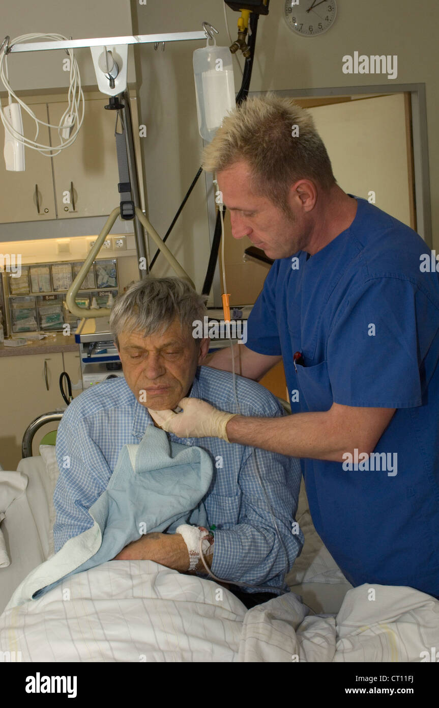 Un anciano se sienta en la cama al final de un procedimiento endoscópico. Foto de stock