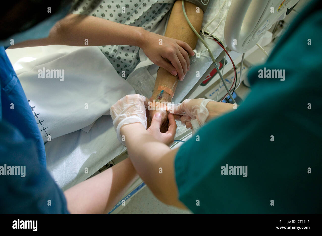 Un paciente tiene un gotero intravenoso insertado en el brazo, en una unidad de cuidados intensivos. Foto de stock
