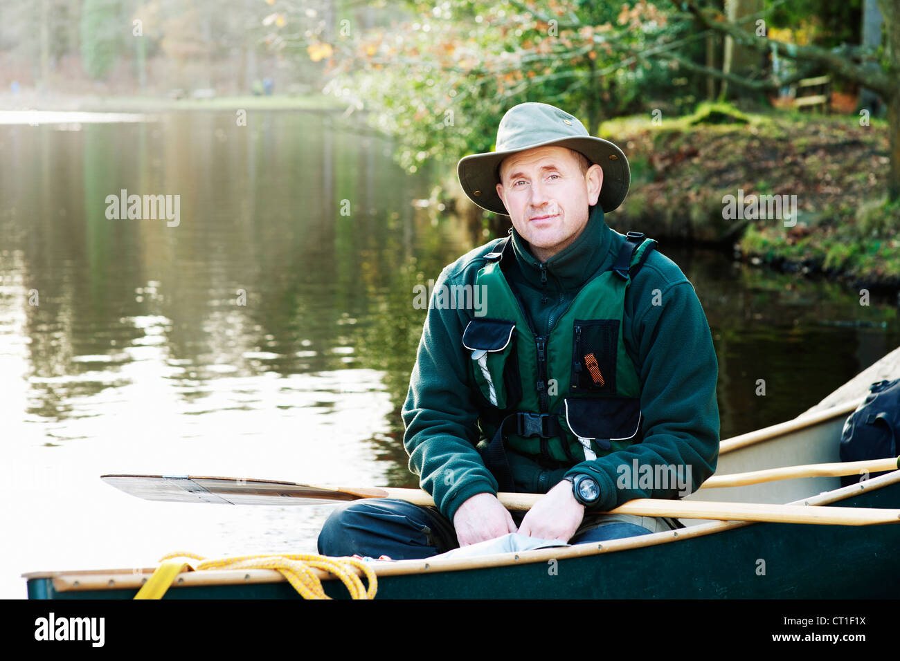 Hombre sentado en canoa en el lago todavía Foto de stock