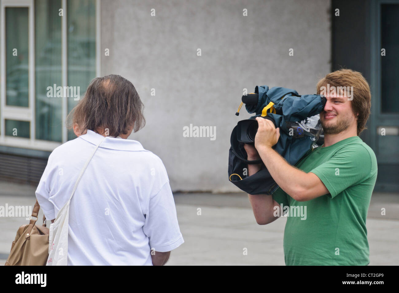 Equipo de TV entrevista en la calle camarógrafo masculino con hombre caucásico en público - Heilbronn, Alemania Foto de stock