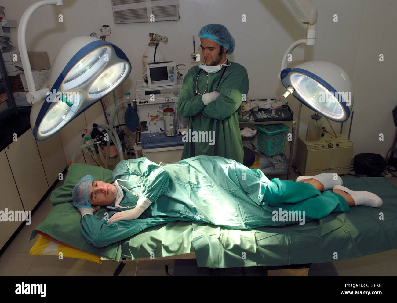 Un estudiante impresionan médico observa como su colleage duerme en una mesa de operaciones. Foto de stock