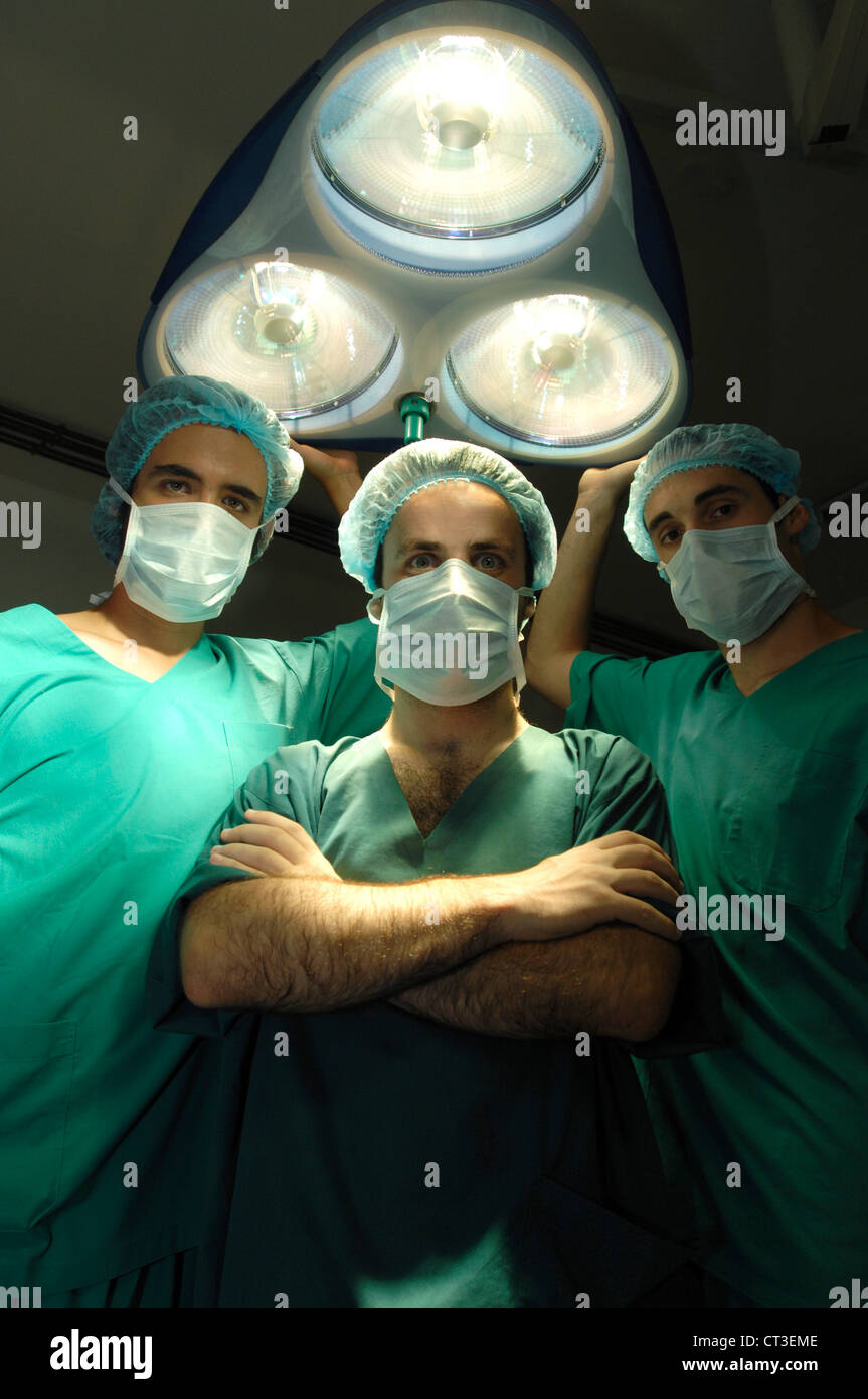 Tres cirujanos de pie debajo de un teatro de luz. Foto de stock