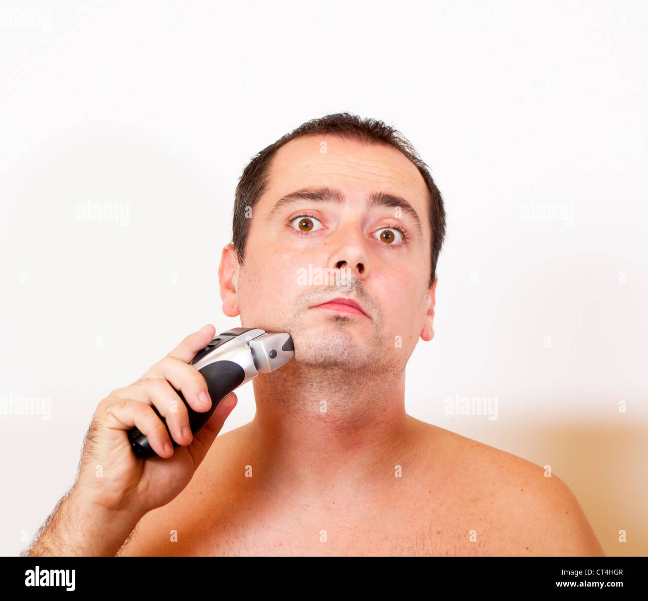 Hombre afeitarse la barba con una máquina de afeitar eléctrica
