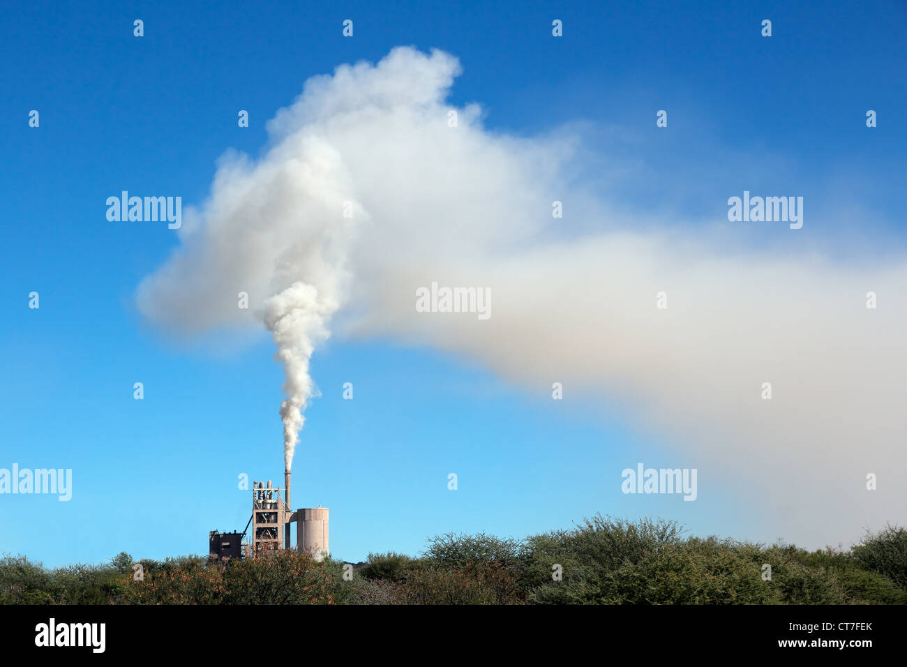 El humo de una planta industrial a la deriva en el viento contra un cielo azul Foto de stock
