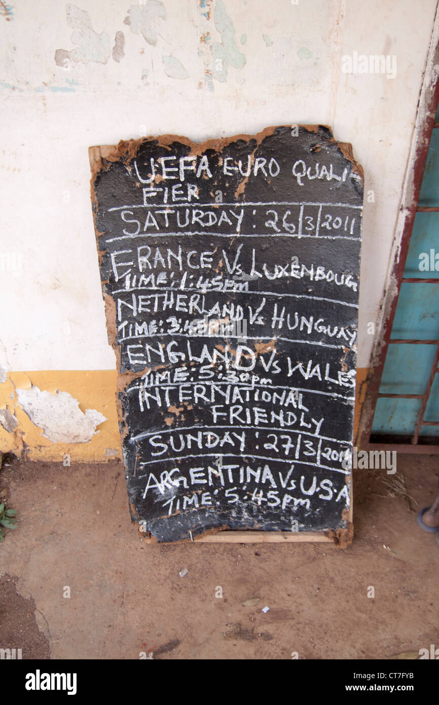 Cartel mostrando que los juegos de fútbol se juega en la aldea local de televisión sobre llegando tarde en Migori, Kenya. Foto de stock