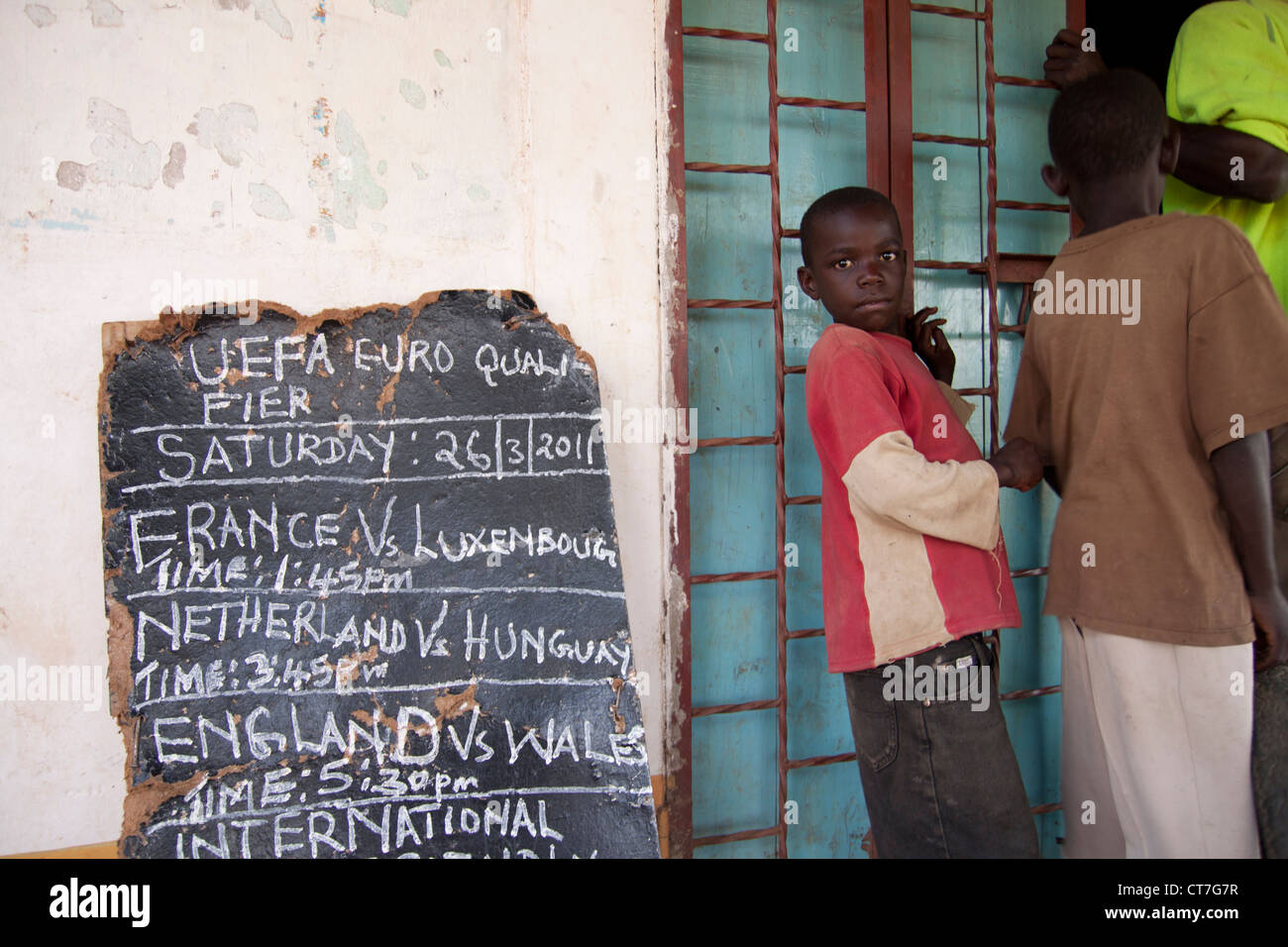 Cartel mostrando que los juegos de fútbol se juega en la aldea local de televisión sobre llegando tarde en Migori, Kenya. Foto de stock