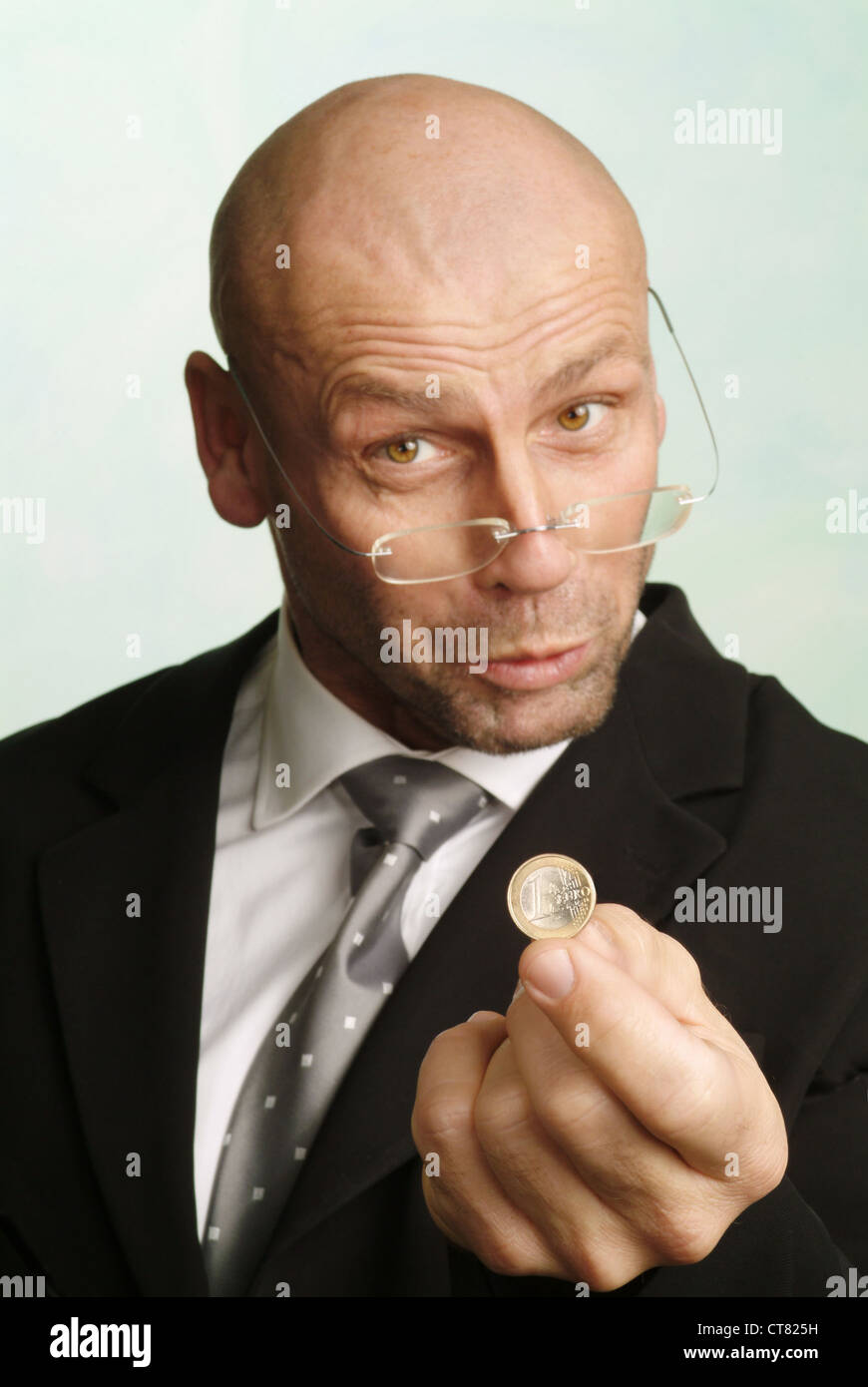 Hombre con 1 euro pedazo en la mano Foto de stock