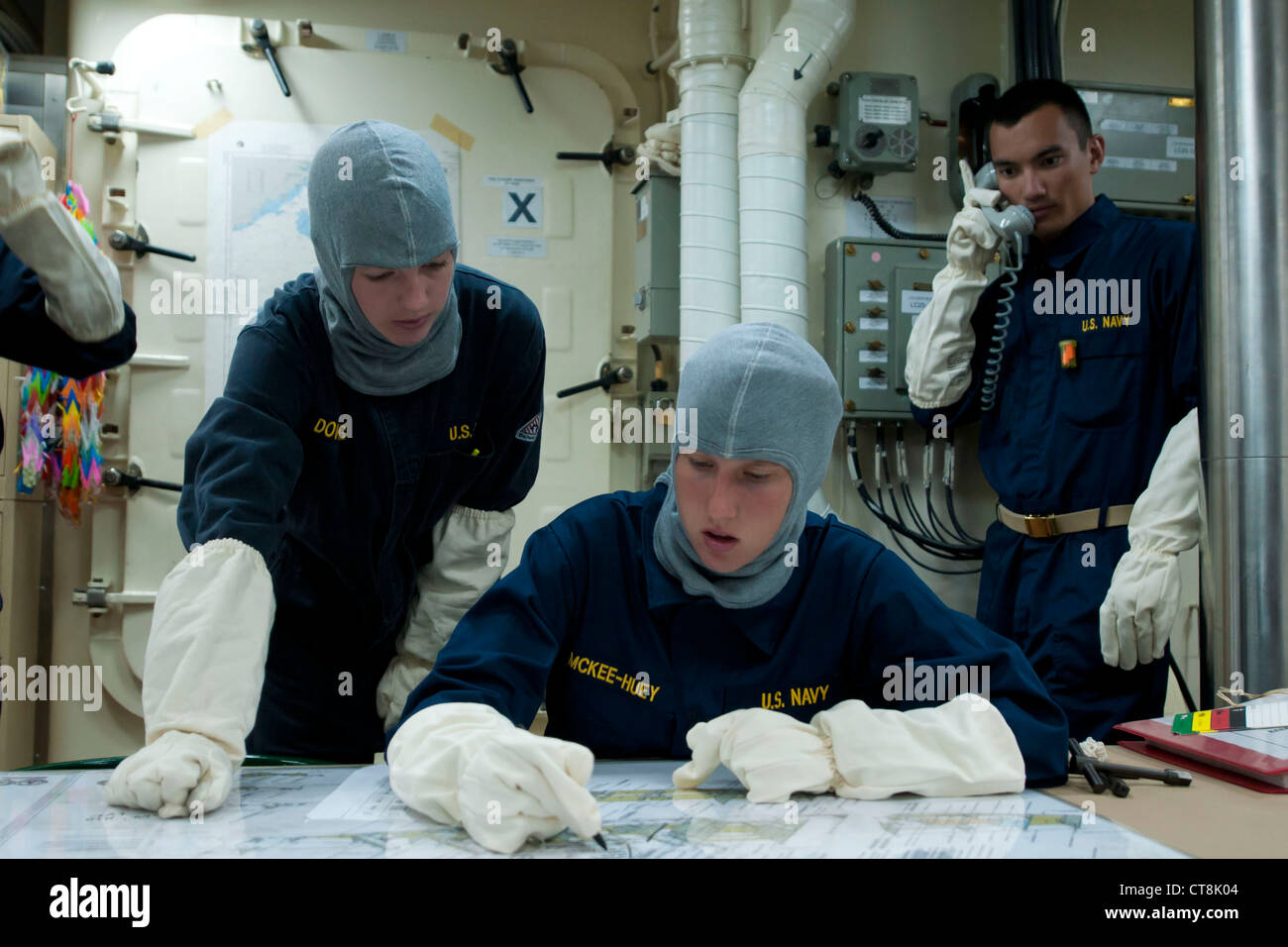 Ensign Elizabeth Downing, de izquierda, oficial electricista asignado al destructor de misiles guiados USS McCampbell de la clase Arleigh Burke (DDG 85), ayuda a Midshipman Margaret McKee-Huey a trazar espacios asegurados durante un simulacro de cuartos generales. McCampbell está desplegado hacia adelante en Yokosuka, Japón, y está en marcha en el área de responsabilidad de la 7a flota de los Estados Unidos. Foto de stock