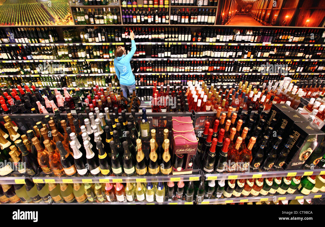 La mujer está de compras en un supermercado grande. Departamento de bebidas, bebidas alcohólicas, bebidas alcohólicas, vino, champagne. Foto de stock
