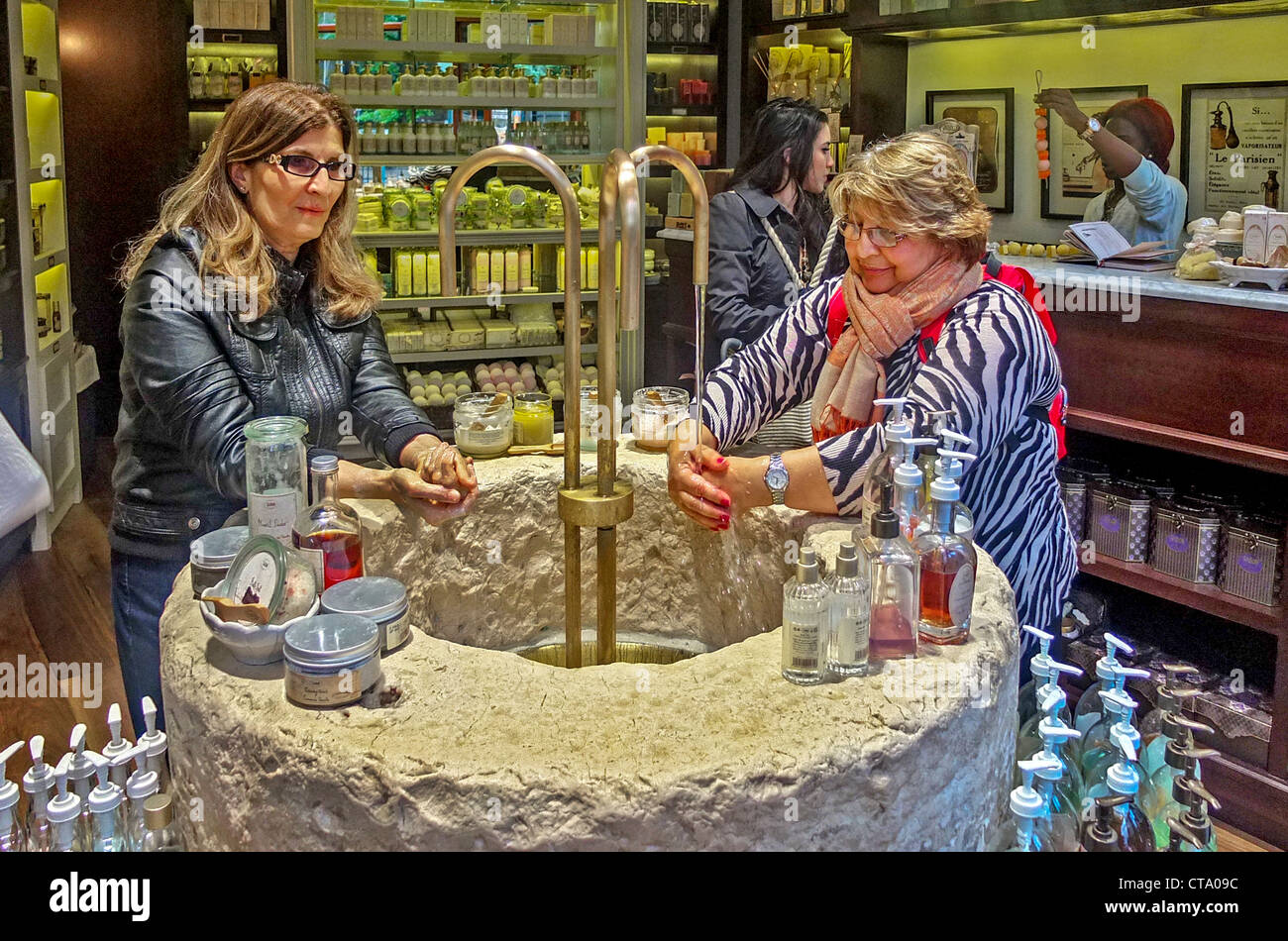 En una tienda de jabón francés importado, Manhattan, Ciudad de Nueva York, las mujeres clientes probar los productos en un fregadero de piedra ornamental. Foto de stock