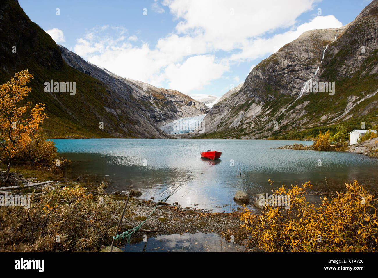 Vista de Nigardsbreen, el barco rojo sobre un lago en frente del glaciar hocico, Otoño, Nigardsbreen, parque nacional Jostedalsbreen, Jost Foto de stock