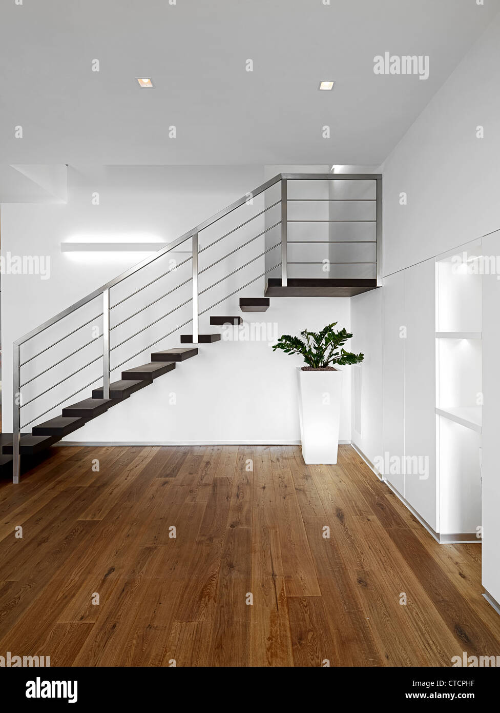Entrada moderna con escalera y piso de madera Foto de stock