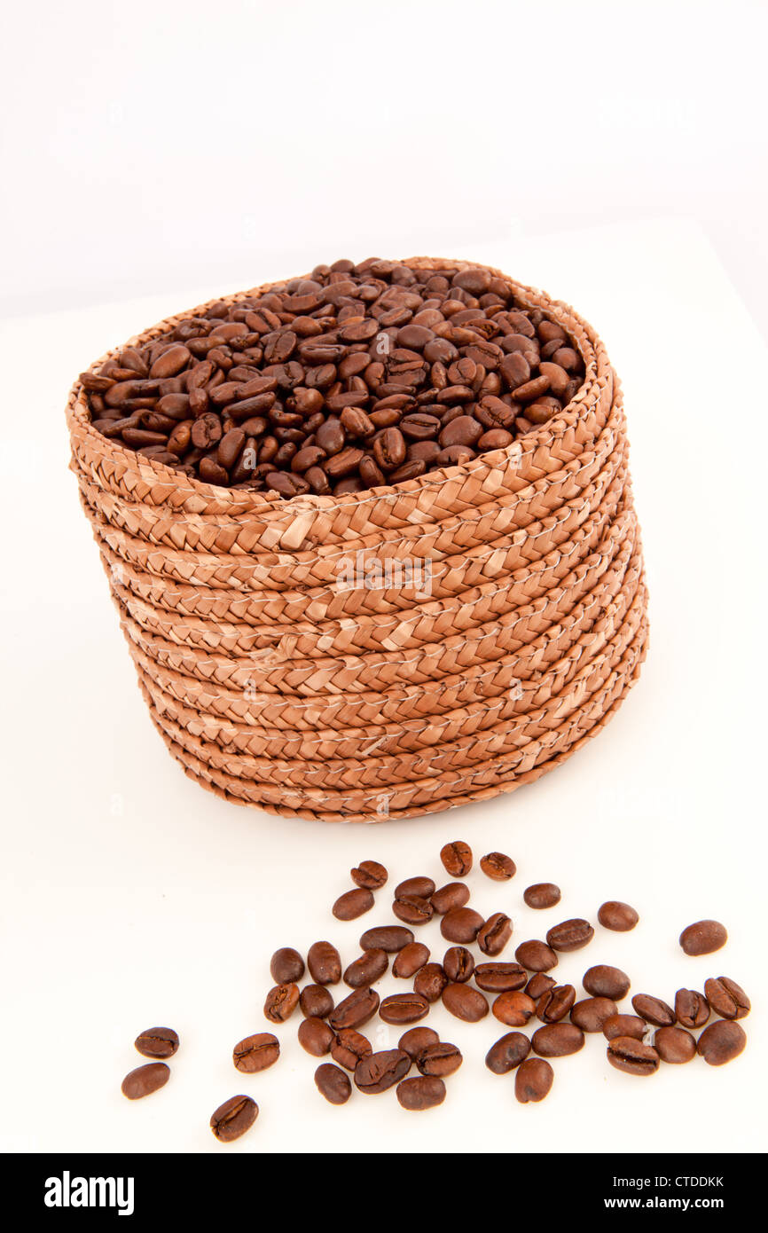 Cerca de una canasta llena de semillas de café con semillas tumbado delante de él. Foto de stock