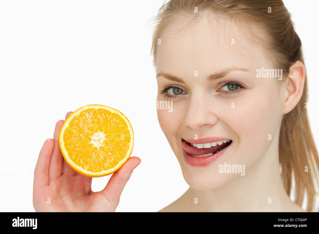Mujer sosteniendo una naranja mientras se coloca su lengua sobre sus labios Foto de stock